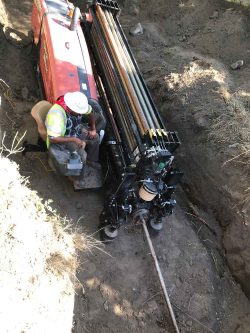 machine placing pipe underground
